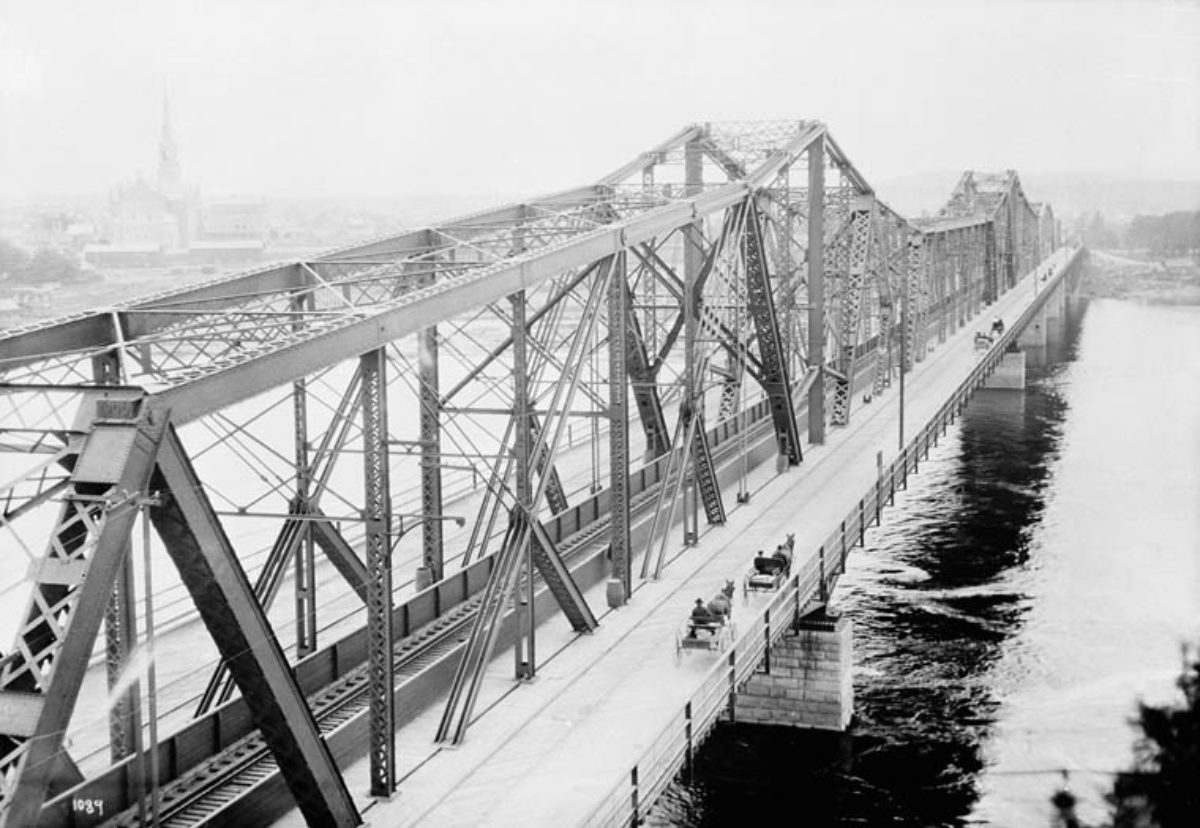 Une image historique du pont Alexandra qui montre des voitures à cheval traversant le côté est du pont, vers 1900.